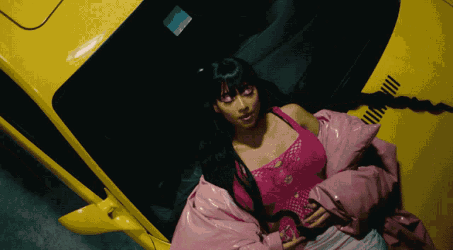 a woman in a pink jacket sits in the back of a yellow car