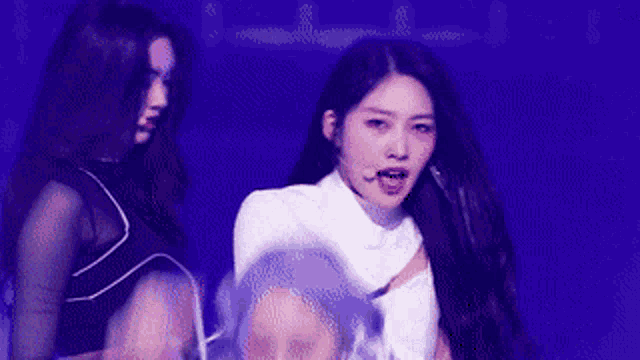 two women are standing next to each other on a stage and one has a microphone in her hand