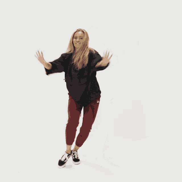 a woman wearing a black jacket and maroon pants is dancing