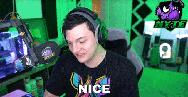 a man wearing headphones is sitting in front of a microphone and saying nice .