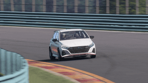 a white car is driving on a race track with a person in the driver 's seat