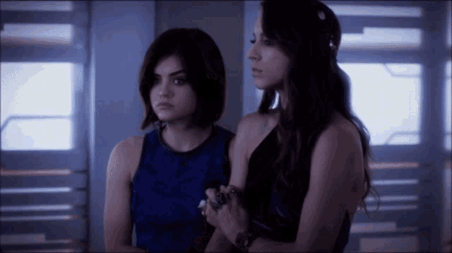two women are standing next to each other in a room