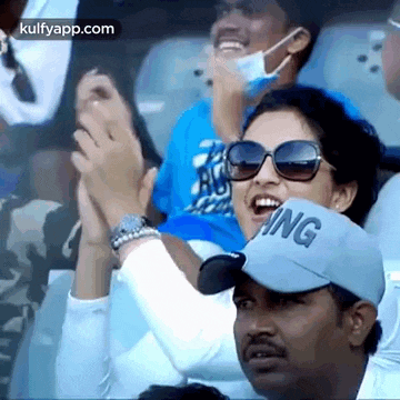 a group of people are sitting in a stadium applauding a cricket game .