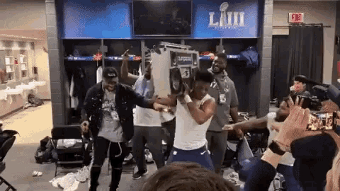 a group of people are dancing in a locker room with a sign that says super bowl lvii