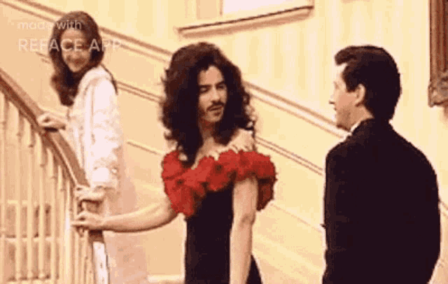 a man in a red dress is standing next to a woman in a white dress and a man in a black suit .