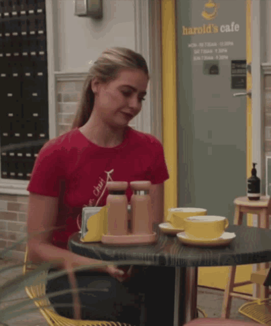 a woman sits at a table in front of a harold 's cafe