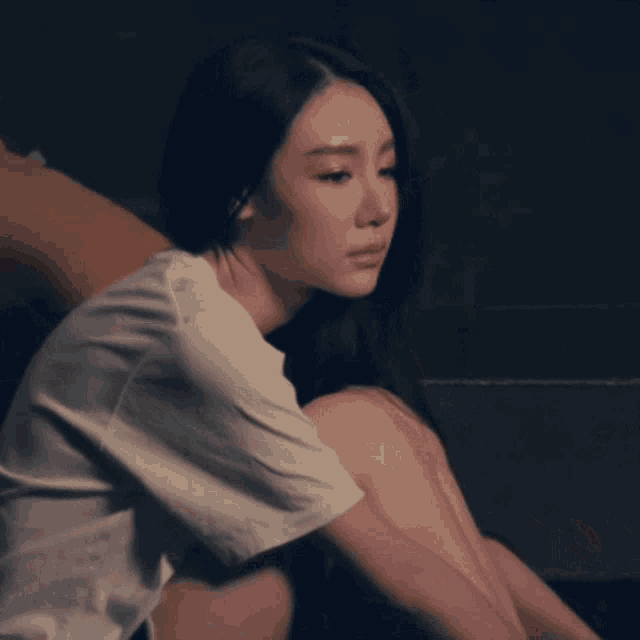 a woman is sitting on the floor with her head on her knees