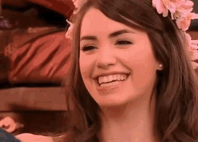 a close up of a woman wearing a flower crown on her head and smiling .