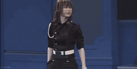 a woman in a black uniform is standing next to a woman in a white suit on a stage .