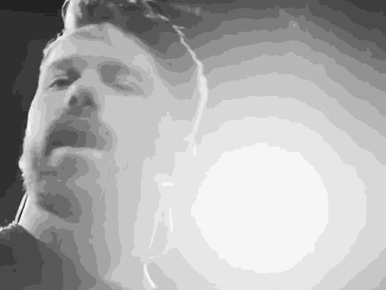 a man with a beard is singing into a microphone in a dark room
