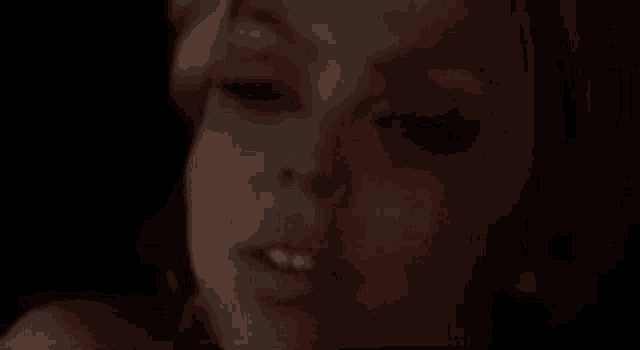 a close up of a woman 's face with her eyes closed and a red background .