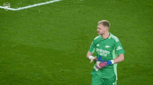 a soccer player in a green jersey is standing next to another player in a red jersey on a soccer field .