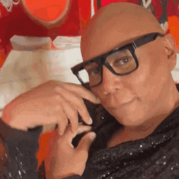 a close up of a bald man wearing glasses and a black shirt .