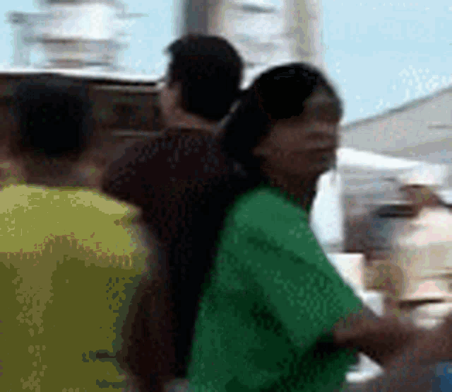 a woman in a green shirt is standing in a crowd .
