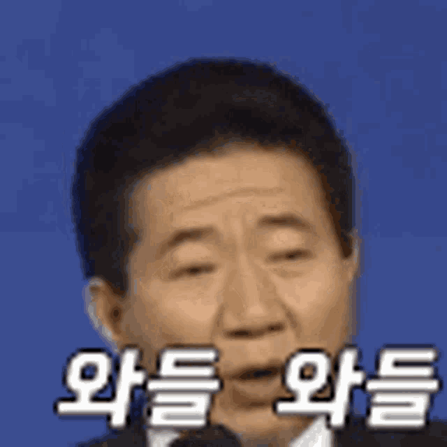 a man in a suit and tie is speaking into a microphone with korean writing on it .
