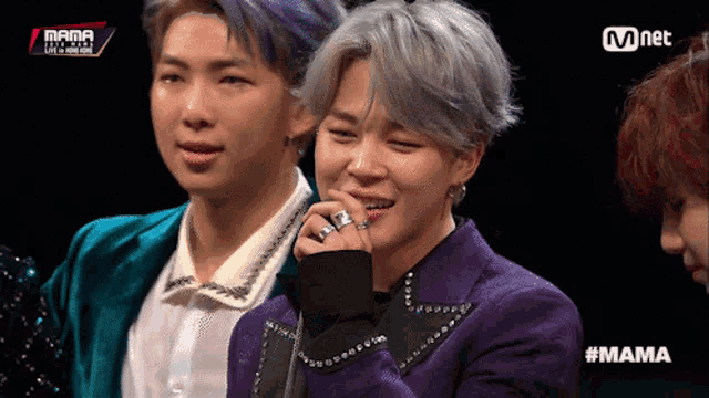 a man in a purple jacket is smiling while sitting next to another man