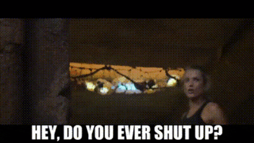 a woman in a black tank top is standing next to a man with a sword and says hey do you ever shut up .