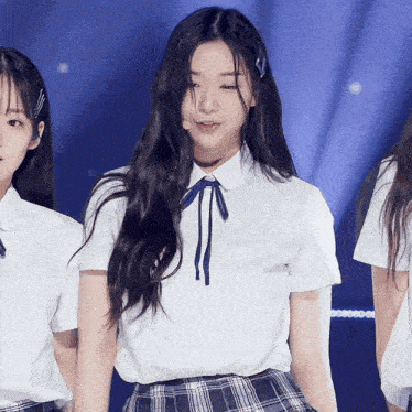 a girl wearing a plaid skirt and a white shirt with a blue bow