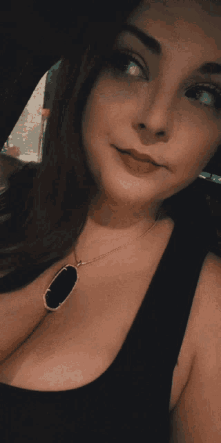 a woman wearing a black tank top with a black pendant