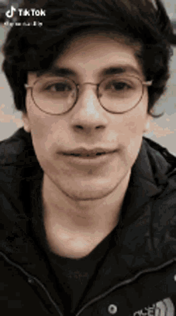 a close up of a man wearing glasses and a black jacket .