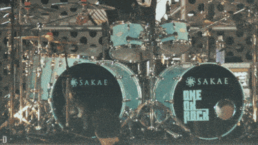 a man stands in front of a sakae one ok rock drum set