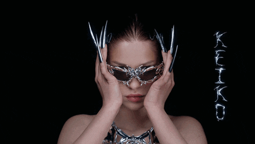 a woman with long nails wearing a mask with the word kiko in the background