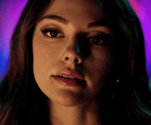 a close up of a woman 's face with a purple and green background