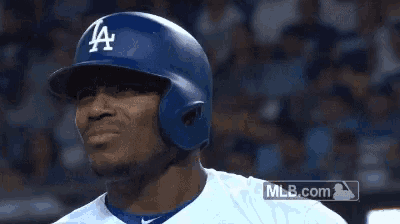 a baseball player wearing a la helmet looks to his left