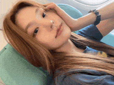 a woman wearing a watch is laying on a chair with her hand on her face