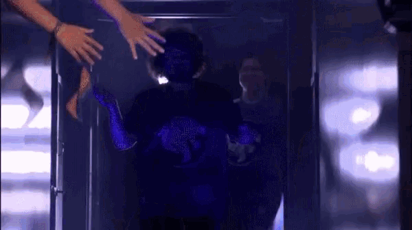 a person in a purple shirt is being reached out by someone 's hands