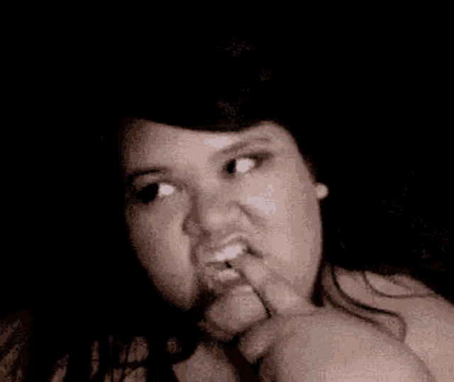 a woman is making a funny face while biting her nails .