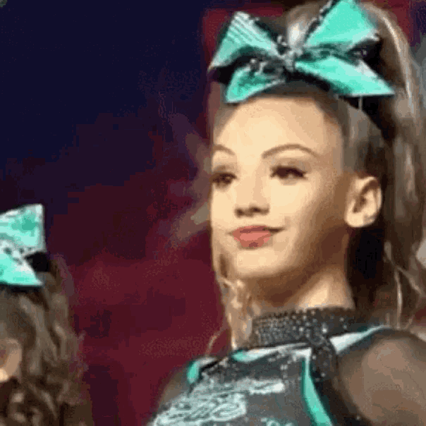 a cheerleader wearing a green bow in her hair is smiling .