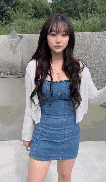 a woman in a blue dress and white cardigan