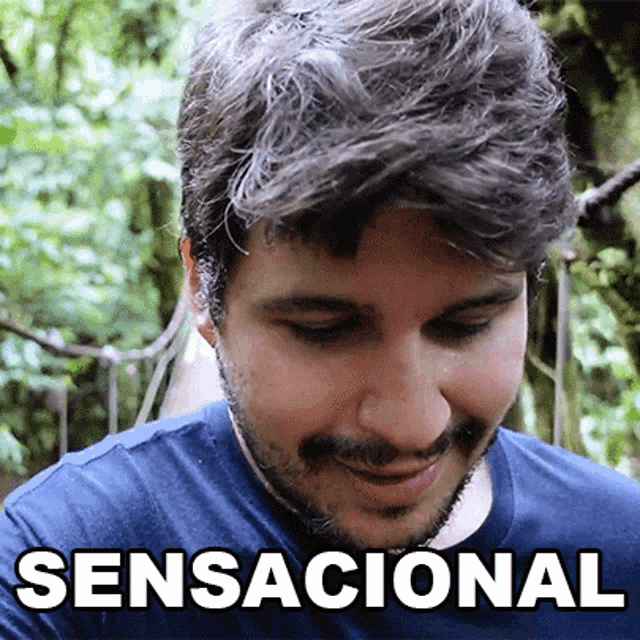 a man with a beard wearing a blue shirt with the word sensacional on it