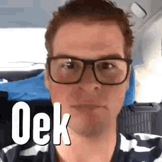 a man wearing glasses and a striped shirt is making a funny face in a car .
