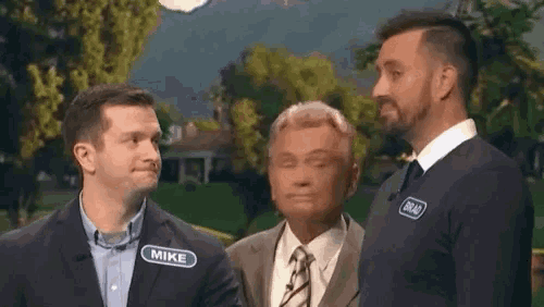 three men are standing next to each other and one of them has a name tag that says mike on it .