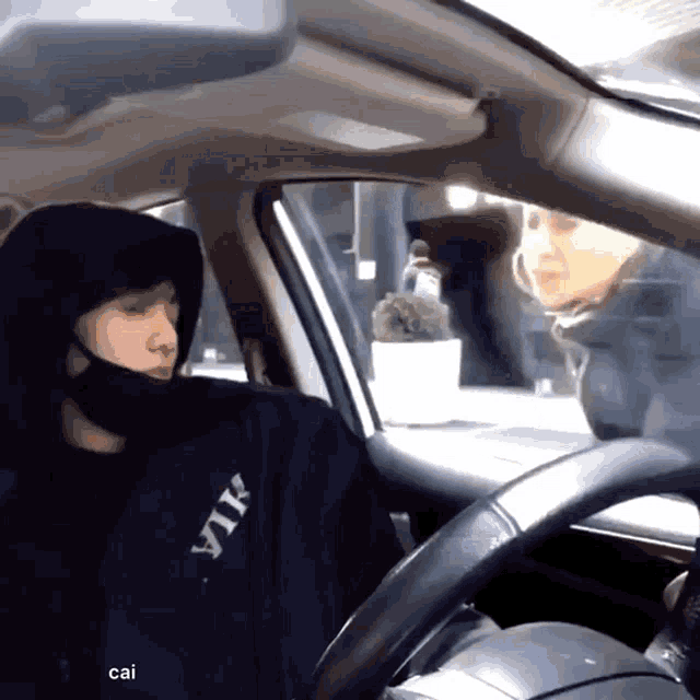 a man wearing a black jacket that says ytk sits in a car