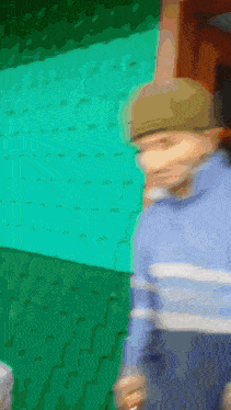a blurry picture of a person wearing a hat and a blue sweater