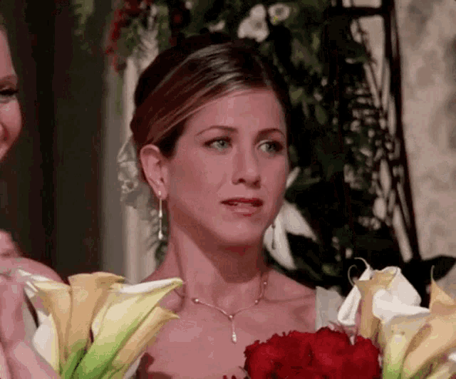 a woman in a wedding dress is holding a bouquet of red roses .