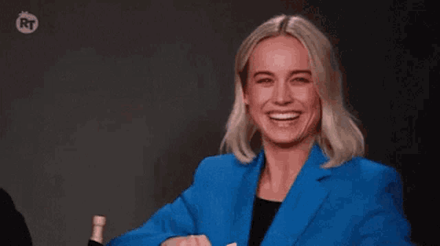 a woman in a blue suit is giving a thumbs up .