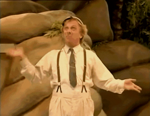 a man in a white shirt and suspenders is standing in front of a wall