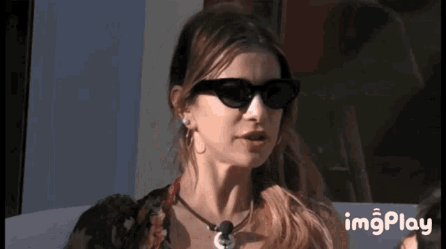 a woman wearing sunglasses and a necklace is being displayed on a screen that says imgplay