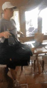a man in a baseball cap is holding a black bag