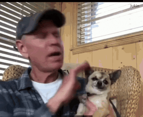 a man is sitting in a chair with a small dog in his lap