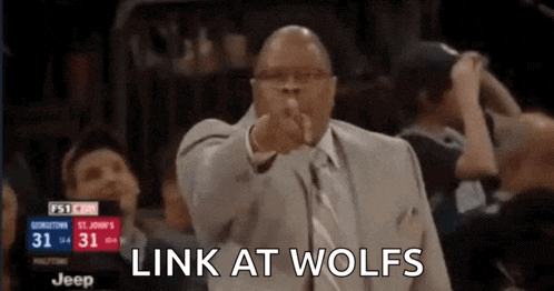 a man in a suit and tie is pointing at the camera with the words link at wolves written below him