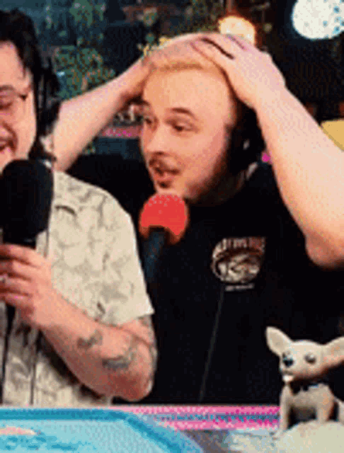 a man wearing headphones is talking into a microphone while another man looks on ..