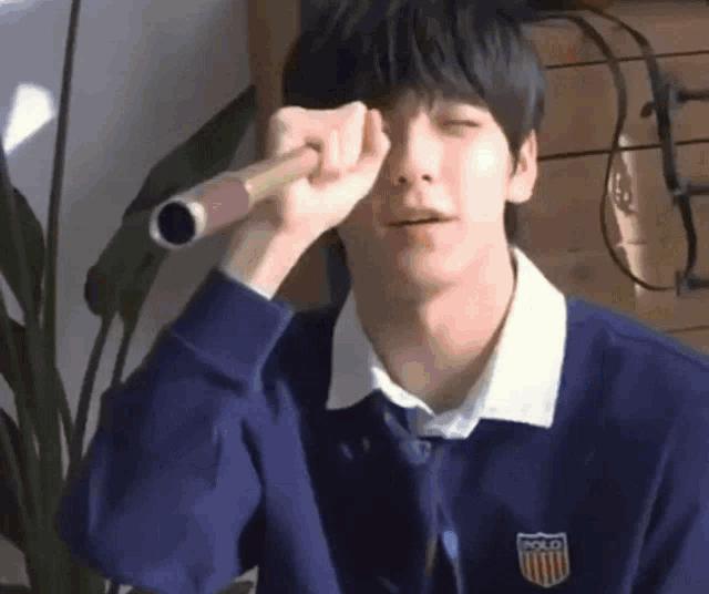 a young man wearing a polo sweatshirt is holding a microphone in front of his face .