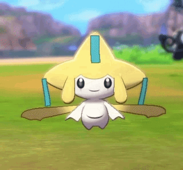 a yellow and white cartoon character with a star on its head is sitting on the grass .