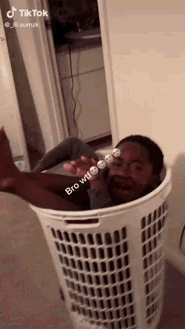 a boy is laying in a laundry basket with the caption bro wtf ..