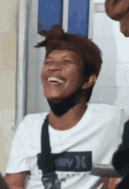 a man wearing a hurley shirt is laughing with his eyes closed